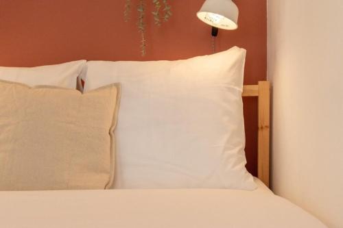 una cama con almohadas blancas y una luz sobre ella en Vieux Lille -Nice studio neat and fully equipped ! en Lille