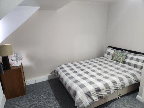 a small bedroom with a bed with a checkered blanket at Tuscawilla 2 in Plumstead