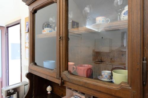 a wooden cabinet with cups and bowls in it at Memoir Appartamento Lecce in Lecce