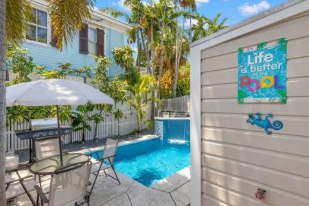 a patio with a table and chairs next to a pool at Poolside Retreat in Key West