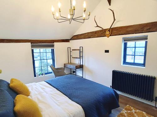 a bedroom with a blue bed and a chandelier at Stansted Airport Cottage in Bishops Stortford