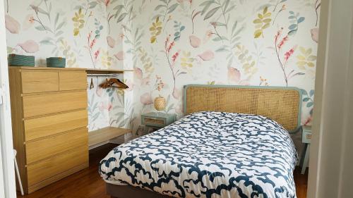 1 dormitorio con cama y papel pintado con motivos florales en Appartement la capitainerie, en Cayeux-sur-Mer