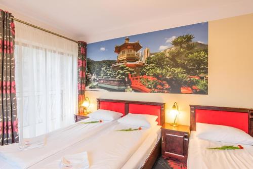two beds in a room with a painting on the wall at Hotel Karolek in Zawoja