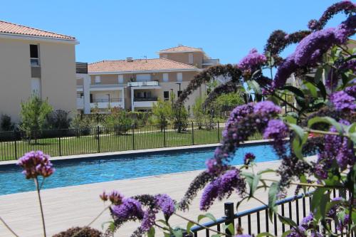 - une vue sur la piscine ornée de fleurs violettes dans l'établissement Très bel appartement pour 3 avec piscine, à La Londe-les-Maures