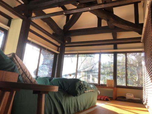a living room with a green couch in a room with windows at 貸切古民家別邸 in Tsukuba