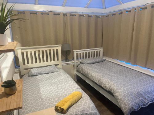 2 camas en una habitación con ventana en Lanarkshire entire house sleeps 6, contractors, trade stays, en Kilsyth