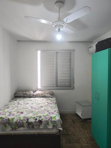 um quarto com uma cama e uma ventoinha de tecto em Astúrias no Guarujá