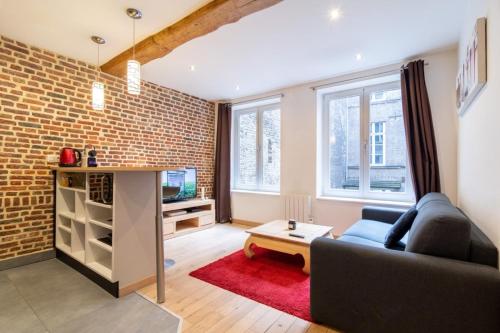 un salon avec un canapé et un mur de briques dans l'établissement Vieux Lille - Appart lumineux avec cachet ! 2pers, à Lille
