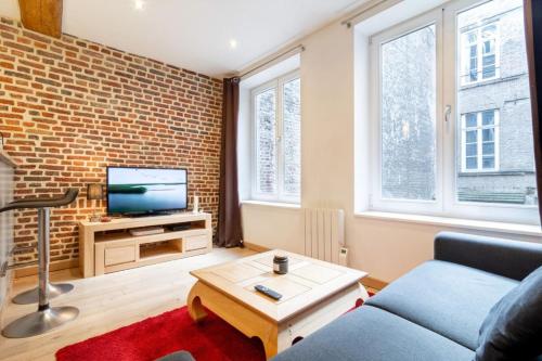 - un salon avec un canapé bleu et un mur en briques dans l'établissement Vieux Lille - Appart lumineux avec cachet ! 2pers, à Lille