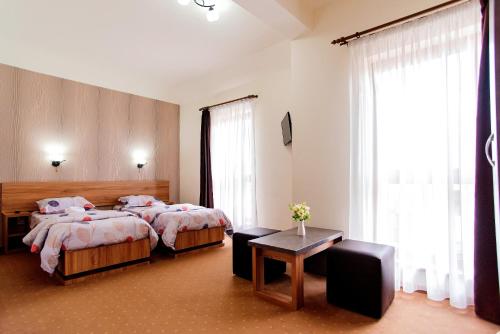 クルジュ・ナポカにあるPensiunea Diadisのベッド2台とテーブルが備わるホテルルームです。