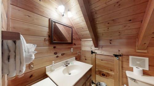 a bathroom with wooden walls and a sink and a mirror at Yellow Cabin on the River in Newport