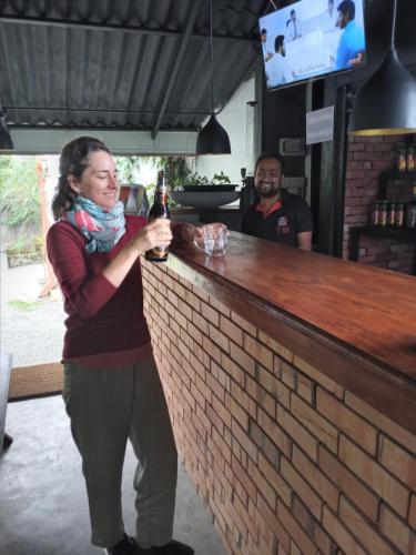 a woman standing at a bar with a bottle of beer at Villa 95 Rangala in Kandy