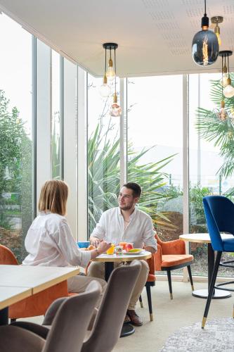 a man and woman sitting at a table in a restaurant at Le Mauritia Hotel et Spa in Pornic