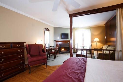 a bedroom with a bed and a chair and a desk at Relais St-Denis in Saint-Sauveur-des-Monts