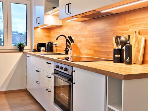 a kitchen with white cabinets and a wooden counter top at Fynbos Deluxe, Penthouse oder Balkon, Parkplatz in Straubing