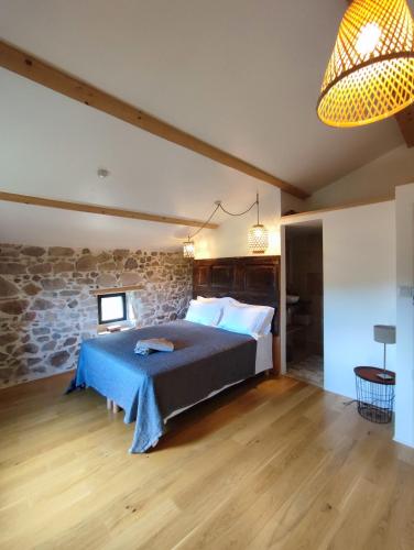 une chambre avec un lit et un mur en pierre dans l'établissement L'atelier des huppes, à Joyeuse