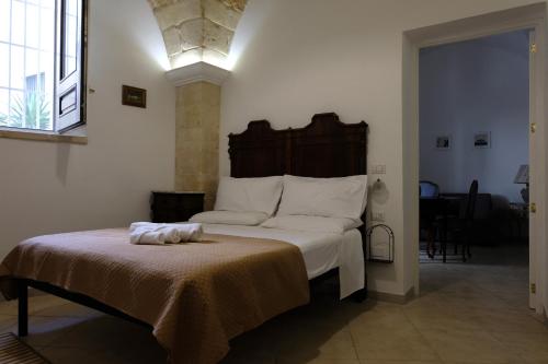 - une chambre avec un grand lit et une tête de lit en bois dans l'établissement Memoir Appartamento Lecce, à Lecce