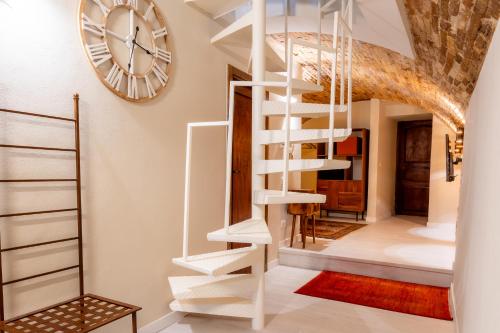 a white spiral staircase in a room with a clock at La Piccola Corte in Spello