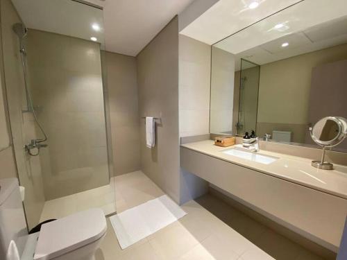 uma casa de banho com um WC, um lavatório e um espelho. em Comfort and minimalism at Yas Island em Abu Dhabi