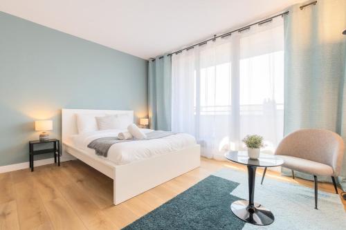 ein Schlafzimmer mit einem weißen Bett, einem Stuhl und einem Tisch in der Unterkunft Close to the city centre - Appartment confortable in Lille