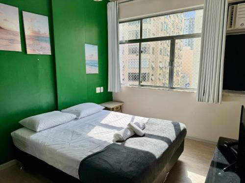 1 dormitorio verde con 1 cama con 2 toallas en Solar do Flamengo 3min Aterro/praia 250 m do metrô, en Río de Janeiro