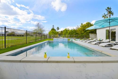 a swimming pool with chairs and a fence at Your Stylish Getaway to Desert Fun and Relaxation in Indio