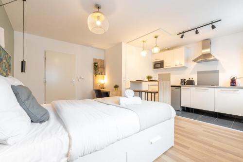 une chambre avec un grand lit blanc et une cuisine dans l'établissement Wazemmes - Functional studio with parking space!, à Lille