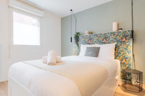 - une chambre blanche avec un grand lit et une tête de lit fleurie dans l'établissement Wazemmes - Functional studio with parking space!, à Lille