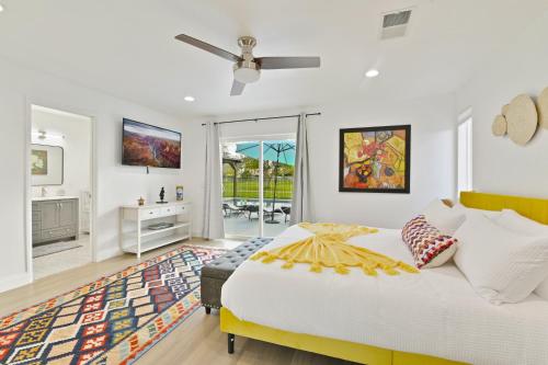 a white bedroom with a bed and a tv at Your Stylish Getaway to Desert Fun and Relaxation in Indio