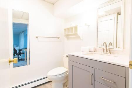 La salle de bains blanche est pourvue de toilettes et d'un lavabo. dans l'établissement Spacious Stone Fire Pit Game Room A C, à Barnstable