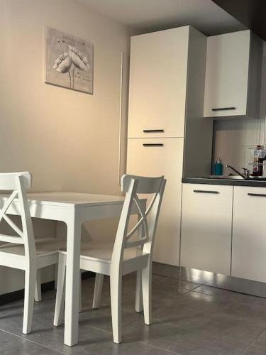 une cuisine avec une table blanche et deux chaises dans l'établissement Un petit cocon de tranquillité, à Mulhouse