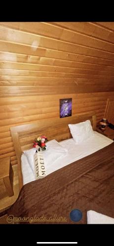 a bed in a wooden room with flowers on it at Moonglade Allure Houses in Polyana