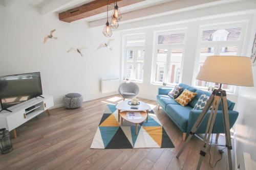 a living room with a blue couch and a tv at Vieux Lille: bright, functional apartment in Lille