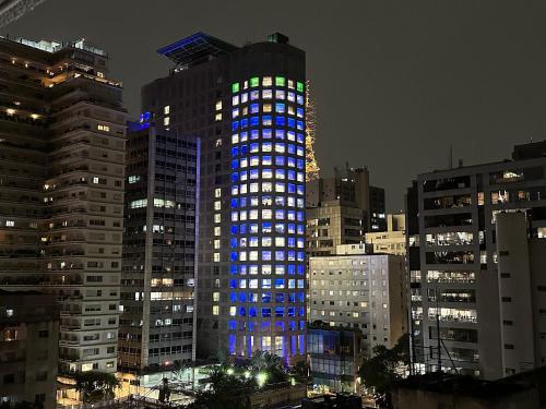 um edifício alto com luzes azuis e verdes em Ap Luxo Jardins Cd 1714 em São Paulo