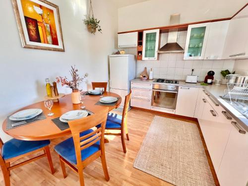Beach Apartment x2 Bedrooms w Sea View & 2x En-Suites في شيبينيك: مطبخ مع طاولة وكراسي ومطبخ مع دواليب بيضاء