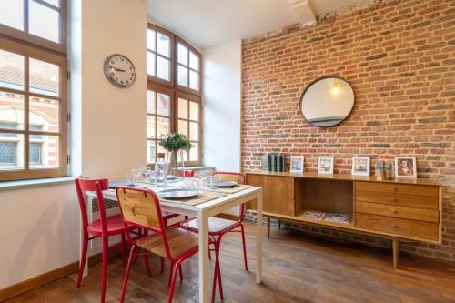 d'une salle à manger avec une table, des chaises et un mur en briques. dans l'établissement Vieux Lille on rue de la Monnaie!, à Lille