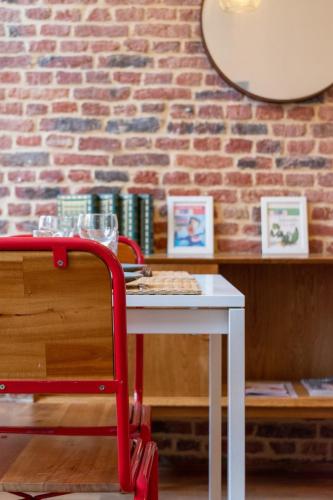 une table blanche avec une chaise rouge devant un mur de briques dans l'établissement Vieux Lille on rue de la Monnaie!, à Lille