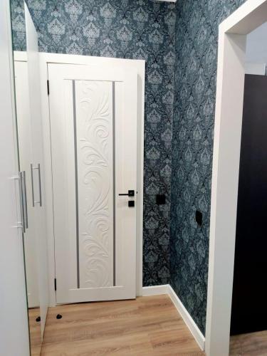 Una puerta blanca en una habitación con papel pintado azul en ЖК Созак. Однокомнатная квартира студия., en Zaozërnyy