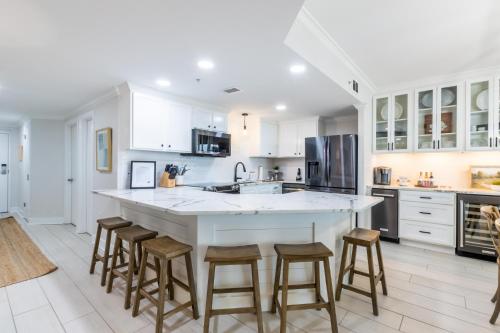una cucina con armadi bianchi e una grande isola con sgabelli da bar di Phoenix X 1403 condo a Orange Beach