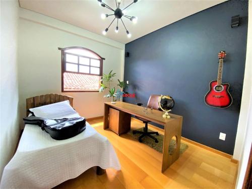 a bedroom with a desk and a guitar on the wall at Apartamento com vista panorâmica in João Monlevade