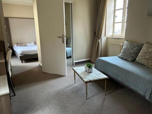 a hotel room with a bed and a table and a window at Cit'Hotel le Challonge in Dinan