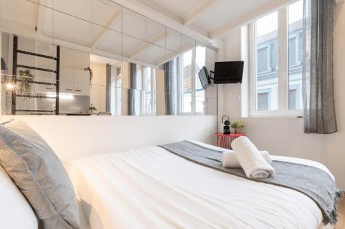 une chambre avec un lit blanc avec un miroir dans l'établissement Lille Saint Maurice - Nice and functional studio, à Lille