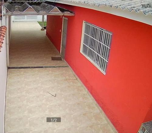 eine rote Wand mit einem Fenster an der Seite eines Hauses in der Unterkunft Casa 3 dorm, prox a 2 praias e da Riviera tb. in Bertioga