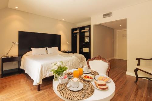 a bedroom with a bed and a table with food on it at Amaike Hotel Golf & Spa in Tandil