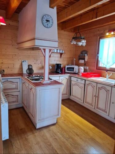 une cuisine avec des placards blancs et une horloge sur une cuisinière dans l'établissement Chalet, Murat (nouveau logement), à Murat
