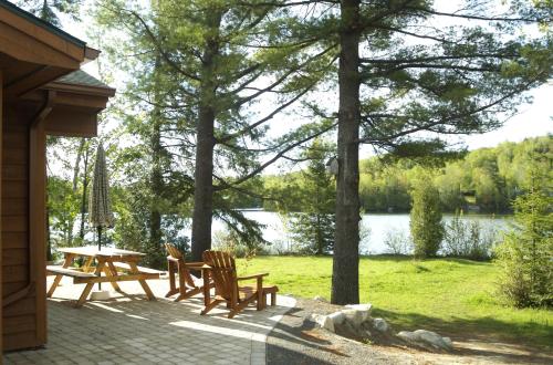 a patio with a table and chairs next to a lake at Les Chalets du Lac Grenier in Chertsey