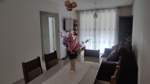 a living room with a vase of flowers on a table at Apartamento em Bombinhas Próximo ao centro e Passarela do Ribeiro in Bombinhas