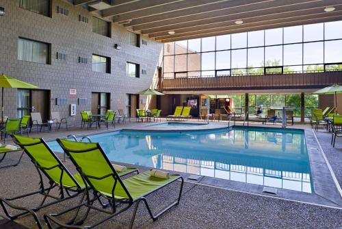 uma piscina num hotel com cadeiras e mesas em Best Western Plus Kelly Inn em Saint Cloud