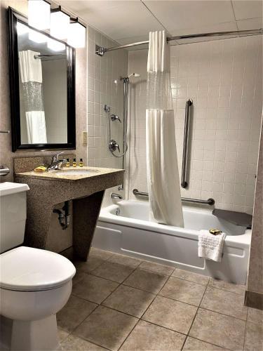 a bathroom with a tub and a toilet and a sink at Best Western Plus Kelly Inn in Saint Cloud