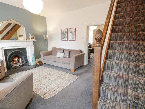 a living room with a staircase and a couch and a fireplace at Swn Yr Afon in Tywyn